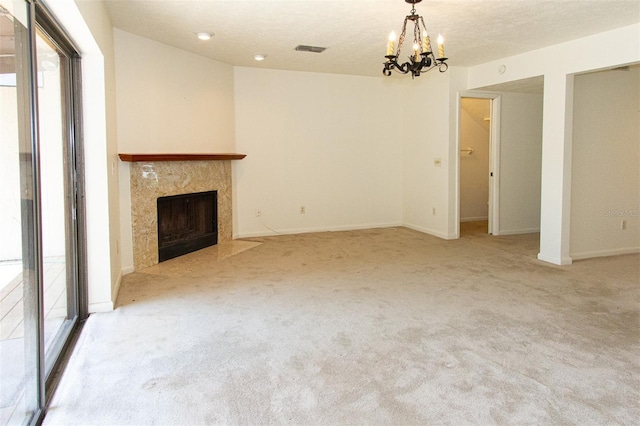 unfurnished living room featuring a high end fireplace, light colored carpet, an inviting chandelier, and a textured ceiling