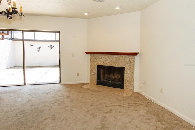 unfurnished living room featuring a fireplace, carpet floors, and a chandelier