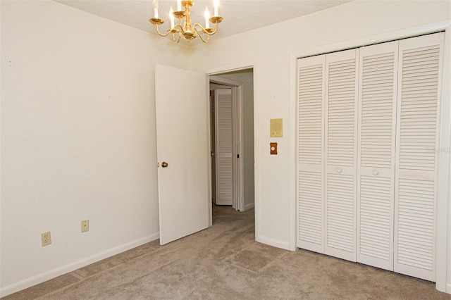 unfurnished bedroom with light carpet, a closet, and a chandelier