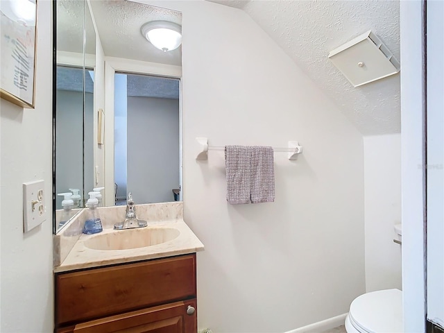 bathroom with vanity, lofted ceiling, toilet, and a textured ceiling