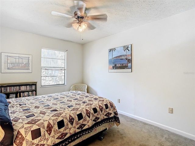 carpeted bedroom featuring ceiling fan and a textured ceiling