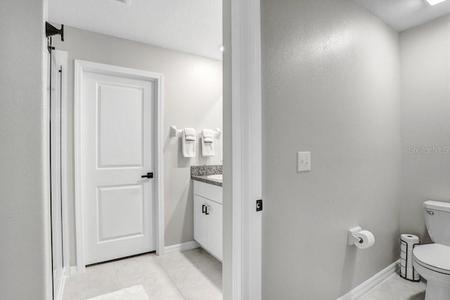 bathroom with toilet, vanity, and tile patterned flooring