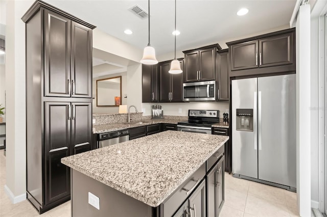 kitchen featuring sink, stainless steel appliances, light stone countertops, a kitchen island, and decorative light fixtures