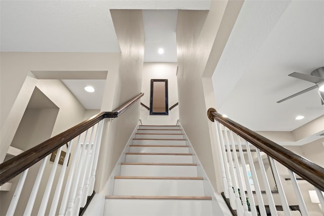 stairs featuring ceiling fan