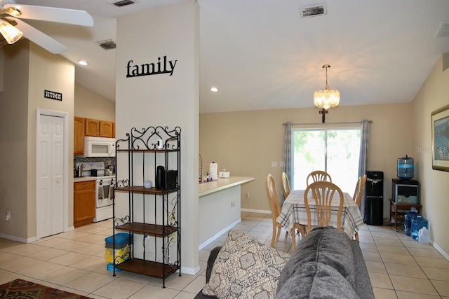 tiled dining space featuring ceiling fan with notable chandelier and lofted ceiling