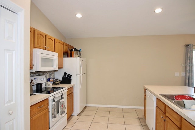 kitchen with light tile patterned flooring, white appliances, vaulted ceiling, and sink