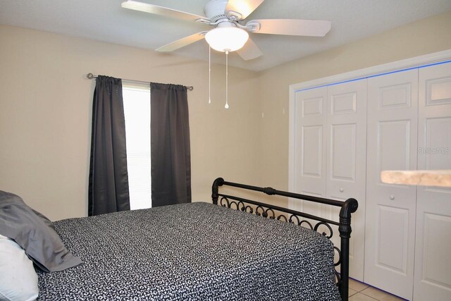 tiled bedroom with ceiling fan and a closet