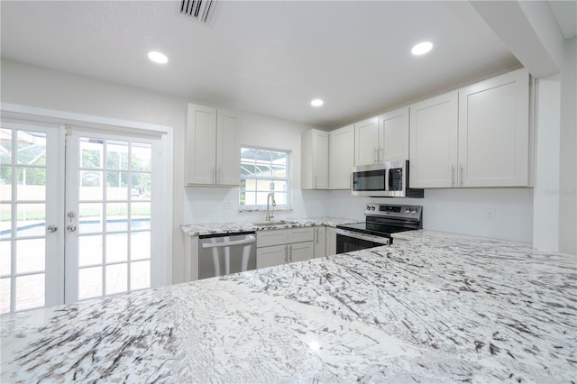 kitchen with appliances with stainless steel finishes, a healthy amount of sunlight, white cabinetry, and sink