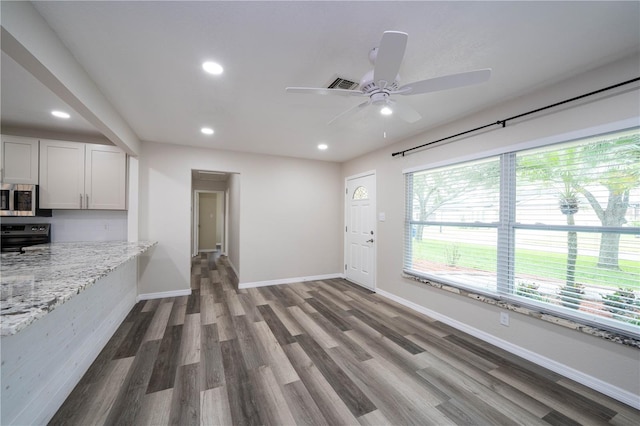 unfurnished living room featuring ceiling fan and dark hardwood / wood-style flooring