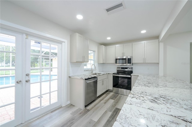 kitchen featuring light stone counters, stainless steel appliances, and white cabinets