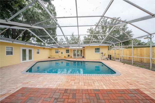 view of pool featuring glass enclosure, french doors, and a patio area