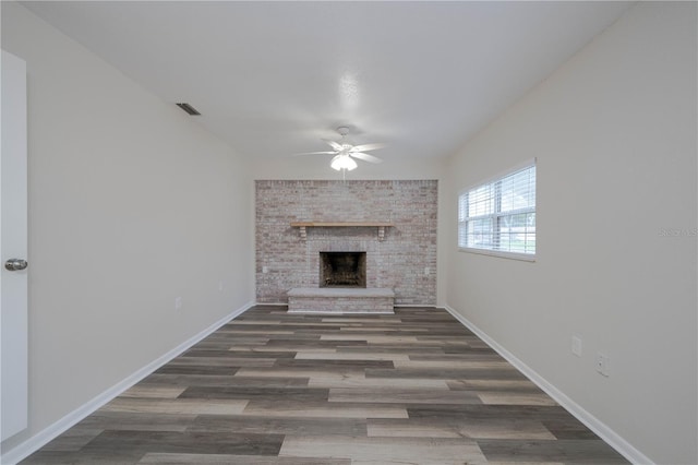 unfurnished living room featuring a fireplace, dark hardwood / wood-style flooring, and ceiling fan