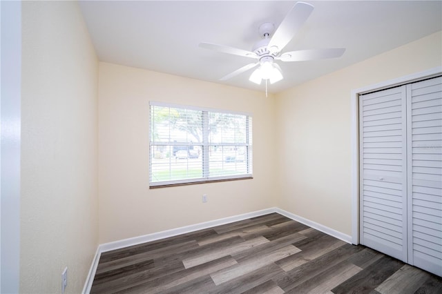 unfurnished bedroom featuring dark wood-type flooring, a closet, and ceiling fan