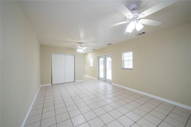 empty room with ceiling fan, french doors, and light tile patterned floors