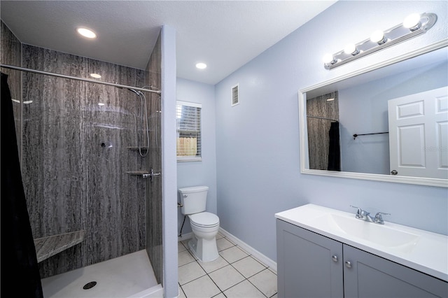 bathroom with tile patterned flooring, toilet, a tile shower, vanity, and a textured ceiling