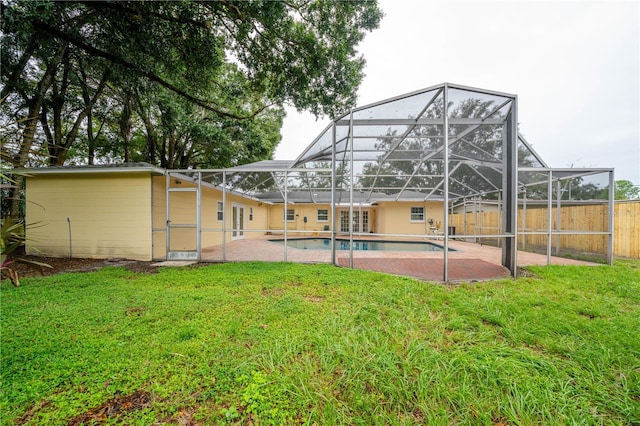 back of house with a fenced in pool, a patio, a lawn, and a lanai