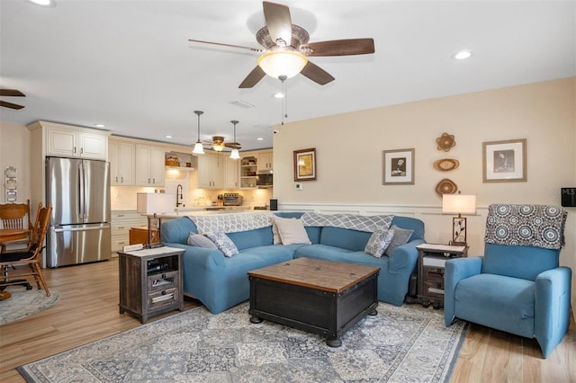 living room with ceiling fan, light wood-type flooring, and sink