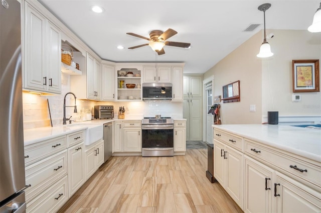 kitchen featuring appliances with stainless steel finishes, backsplash, ceiling fan, sink, and pendant lighting