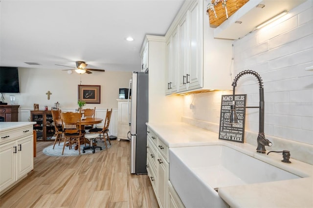 kitchen with stainless steel fridge, ceiling fan, sink, light hardwood / wood-style flooring, and white cabinets