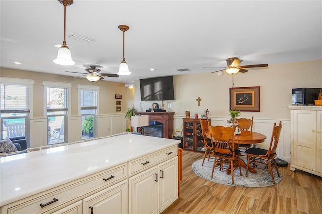 kitchen with decorative light fixtures, light hardwood / wood-style floors, and cream cabinets