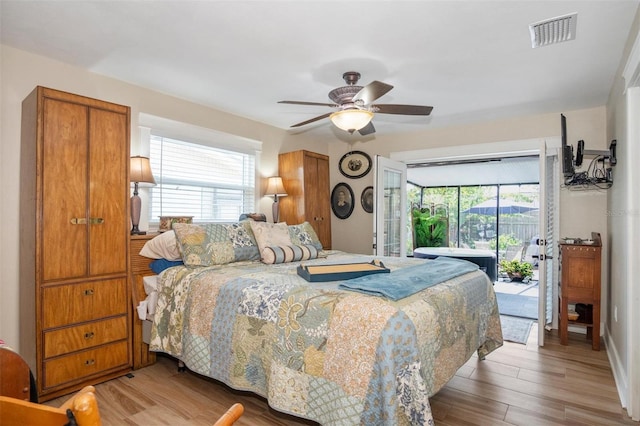 bedroom featuring ceiling fan, access to exterior, wood-type flooring, and multiple windows