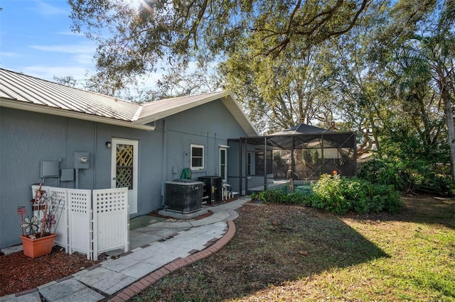 exterior space featuring stucco siding, central air condition unit, a standing seam roof, metal roof, and a lanai