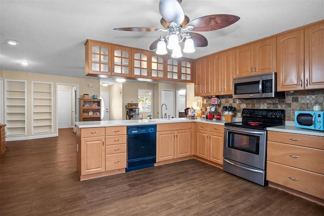 kitchen featuring a peninsula, appliances with stainless steel finishes, a sink, and light countertops