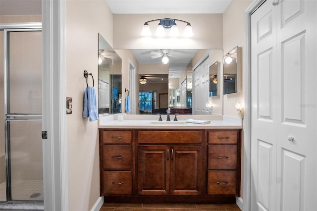 bathroom featuring baseboards, a shower stall, vanity, and a ceiling fan