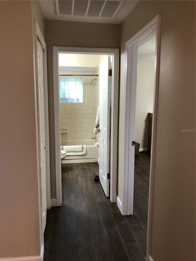 corridor featuring baseboards, visible vents, and dark wood-style flooring