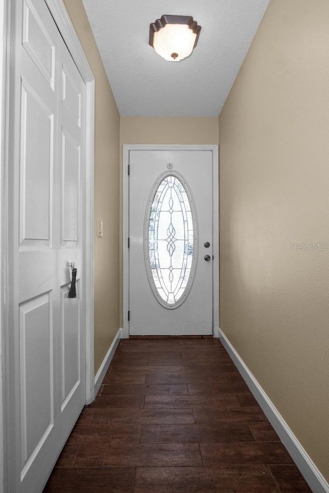 entryway with a textured ceiling, dark wood-type flooring, and baseboards