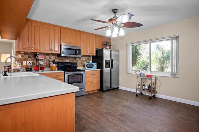 kitchen with stainless steel appliances, a sink, light countertops, tasteful backsplash, and dark wood finished floors