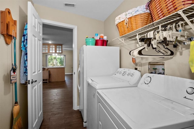 laundry room with laundry area, visible vents, baseboards, washer and clothes dryer, and dark wood finished floors