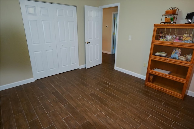 unfurnished bedroom with a closet, dark wood finished floors, and baseboards