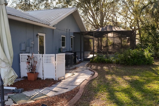 view of property exterior with a sunroom, metal roof, cooling unit, and a yard