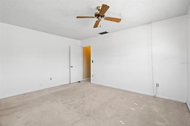 spare room with ceiling fan, a textured ceiling, and light colored carpet