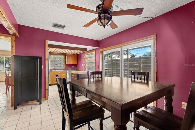 dining space featuring sink, light tile patterned flooring, a textured ceiling, and ceiling fan