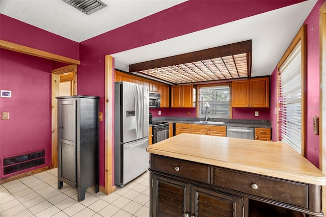 kitchen featuring stainless steel appliances, sink, light tile patterned flooring, and heating unit