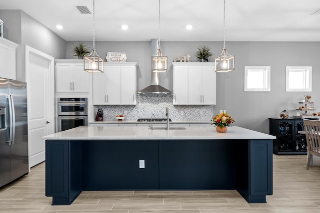 kitchen featuring pendant lighting, white cabinetry, stainless steel appliances, and a kitchen island with sink