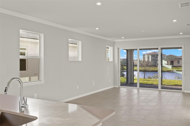 interior space with a healthy amount of sunlight, a water view, crown molding, and sink