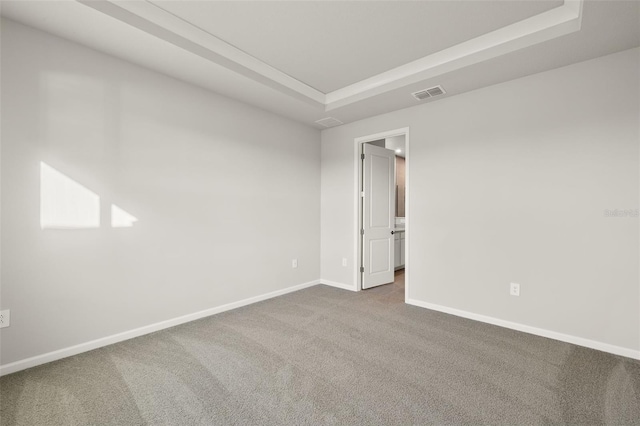 carpeted empty room featuring a raised ceiling