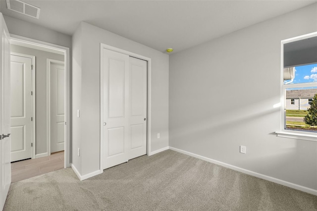 unfurnished bedroom featuring light carpet and a closet