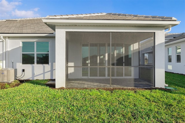 back of property featuring a yard, central air condition unit, and a sunroom