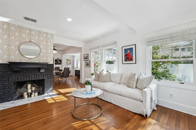 living room with hardwood / wood-style flooring, ornamental molding, and a brick fireplace