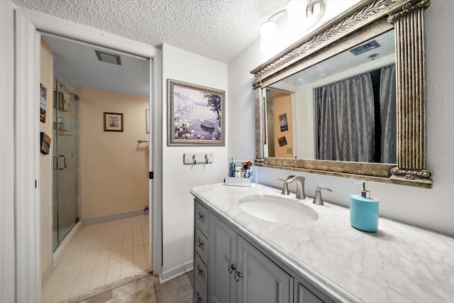 bathroom featuring vanity, a textured ceiling, walk in shower, and tile patterned floors