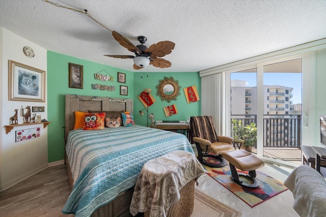 bedroom with ceiling fan, a textured ceiling, access to outside, and wood-type flooring