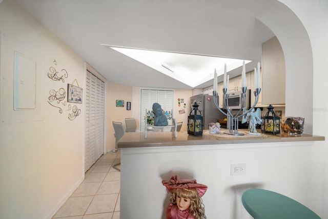 kitchen featuring electric panel, appliances with stainless steel finishes, kitchen peninsula, and light tile patterned floors