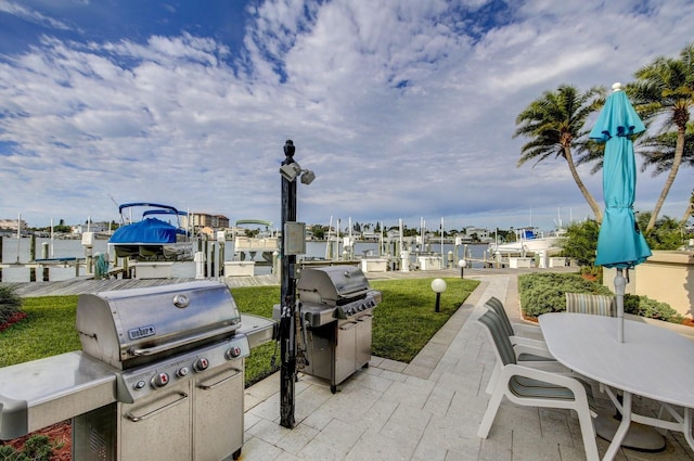 view of patio with area for grilling, a dock, and a water view