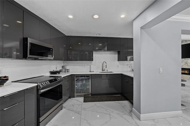 kitchen with sink, wine cooler, a textured ceiling, a fireplace, and stainless steel appliances