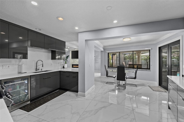 kitchen with decorative backsplash, a textured ceiling, beverage cooler, crown molding, and sink