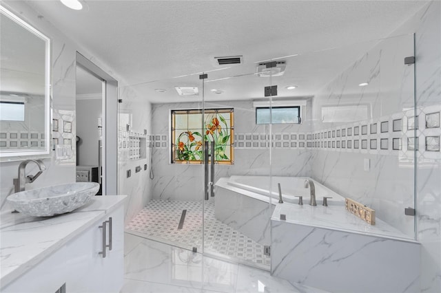 bathroom with plus walk in shower, vanity, a textured ceiling, and tile walls